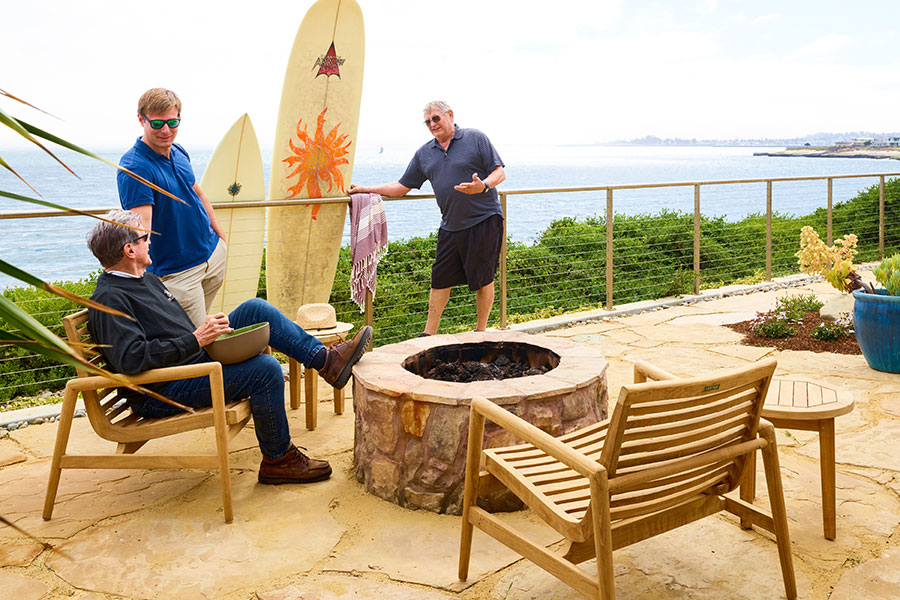 Richie men and surfboards around firepit with Salt Point chairs on Santa Cruz patio