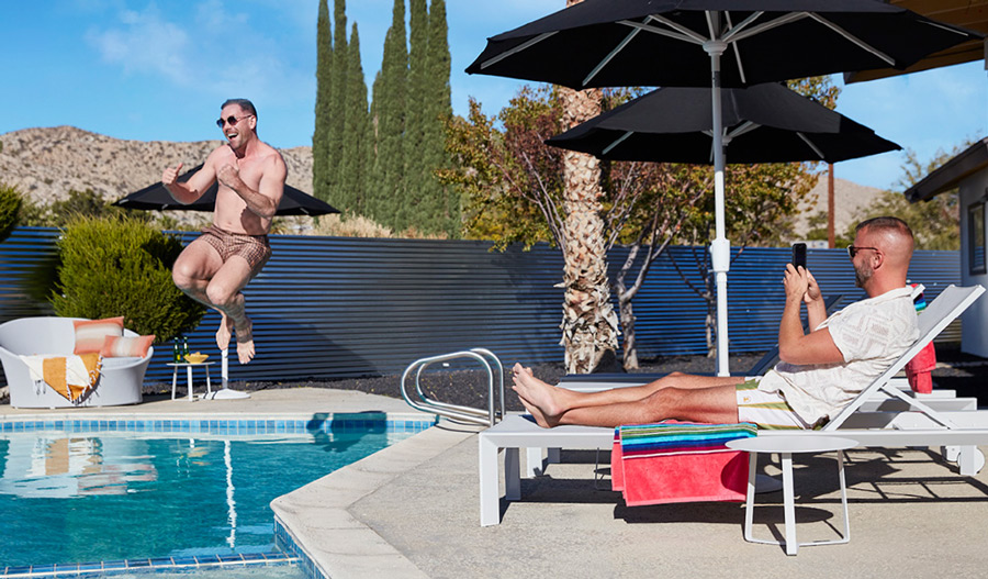 kit cannonballs into the pool as jon looks on in Palm Springs design style