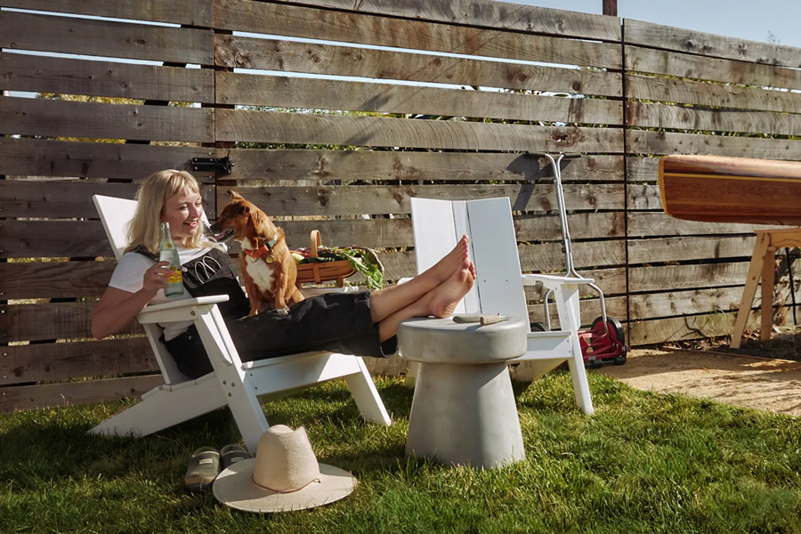 Woman relaxing with dog on Woodside adirondack chair made from recycled plastic