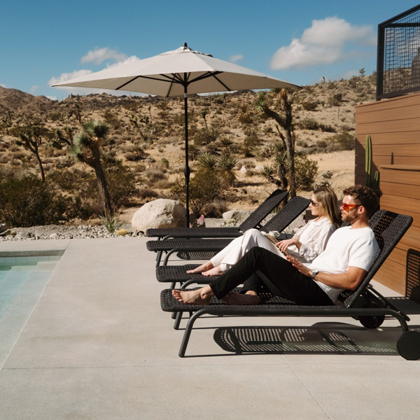 center post umbrella with auto tilt function alongside charcoal toned chaise loungers