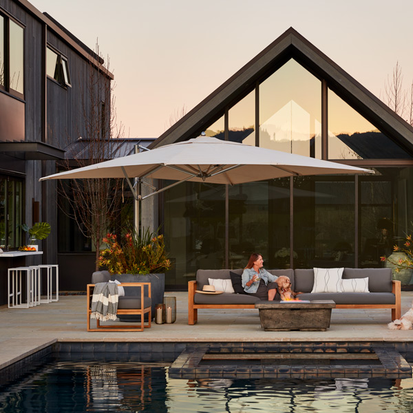 Cantilever umbrella alongside pool with teak lounge furniture and fire table